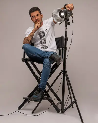 Valmir na cadeira de diretor, ao lado da luz de estúdio
