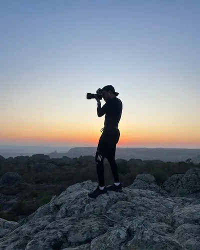 Valmir fotografando ao pôr do sol, em silhueta